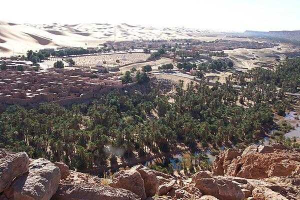 The oasis village of Taghit in the Sahara is known for its surrounding massive dunes. The oasis waters may be seen in the foreground. The site is some 1,100 km (680 mi) southwest of Algiers, and about 145 km (90 mi) north of Beni Abbes.