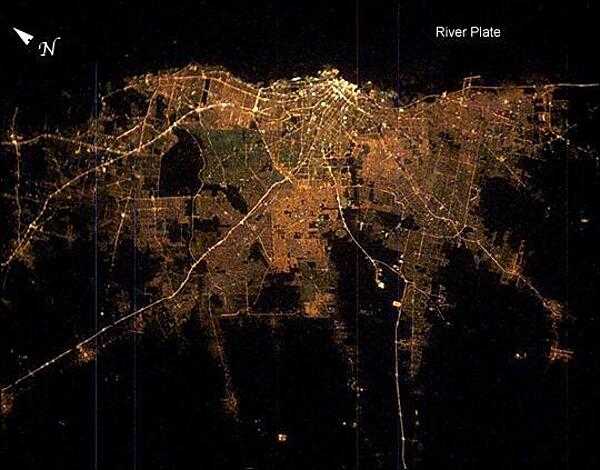 Buenos Aires at night. The brightness of the lights reflects the density of the urban population, which declines to blackness in the farmlands that surround the city. The brightest area is the old part of the city centered on the port and the presidential palace. The blackest part of the scene is the River Plate, the great estuary of the Atlantic Ocean on which this port city is located. The widest city thoroughfare in the world - the Avenida 9 de Julio - is the brightest line in the downtown cluster. It appears as the longest north-south strip just inland of the port. Image courtesy of NASA.
