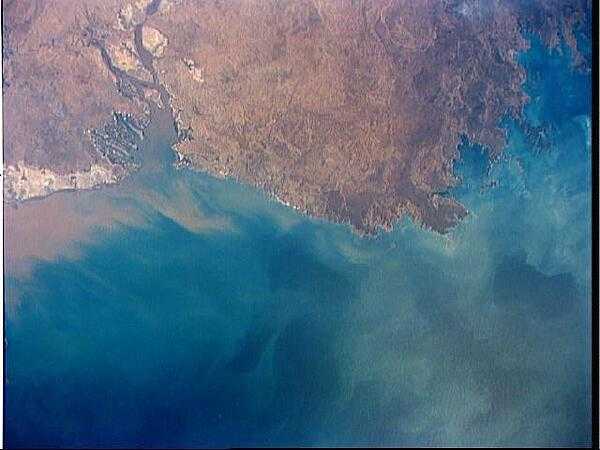 A view of the northern coast of Western Australia shows the low lying coastal plains that surround much of Joseph Bonaparte Gulf, Western Australia. Large plumes of sediment have been washed into the Cambridge Gulf, probably from the Victoria River, which flows into the Gulf just outside the area of the photo. Image courtesy of NASA.