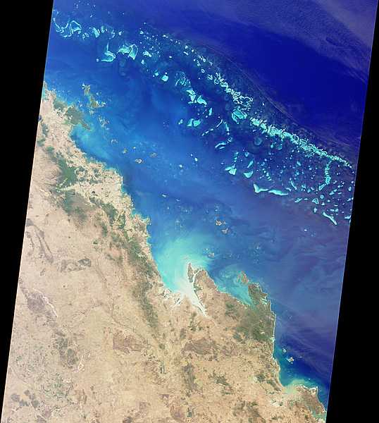 Photo from space showing a section of the northeast Australian coast. The green islands just off the coast in the upper left are the Whitsunday Islands: the myriad strings of isles and reefs running across the top of the image are part of the Great Barrier Reef. Image courtesy of NASA.