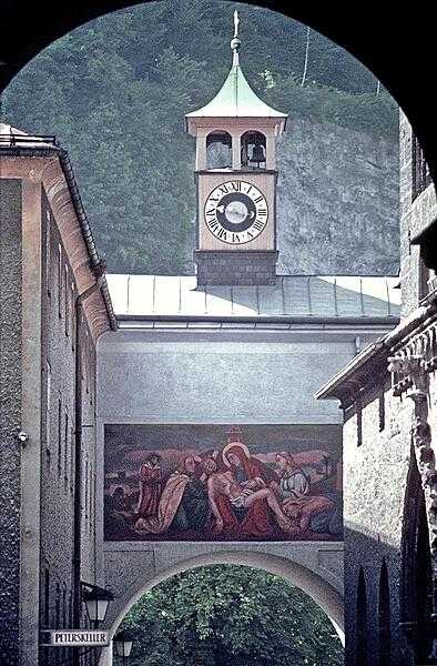 A unique clock archway in Salzburg displays a religious mural.