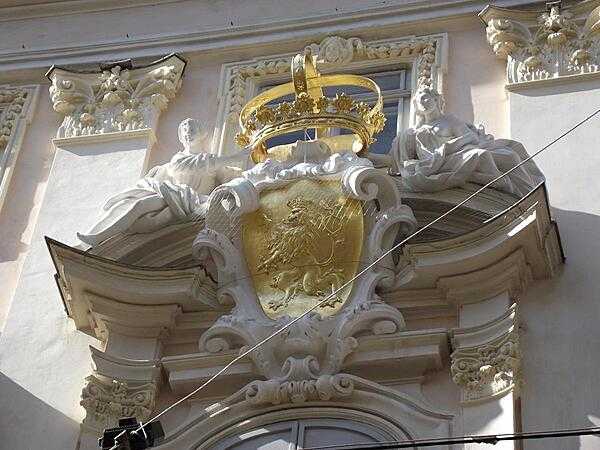 A gilded shield and crown highlight a coat of arms display over a doorway in Vienna.