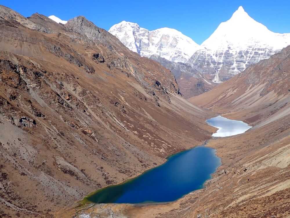 The twin lakes of Tshophu are two of the many lakes in Bhutan formed by melting glaciers. The lakes, located in Jigme Dorji National Park, at an altitude of 4,430 m ( 14,534 ft), are part of the Jomolhari Loop Trek that many visitors to Bhutan walk. The sharp peak on the right is Jichu Drakye, which is 6,989 m (22,893 ft) high; the middle peak is Jomolhari 2, standing at 6,942 m ( 22,775 ft), and the tip of Jomolhari at 7,134 m (23,996 ft) is just visible to the left.