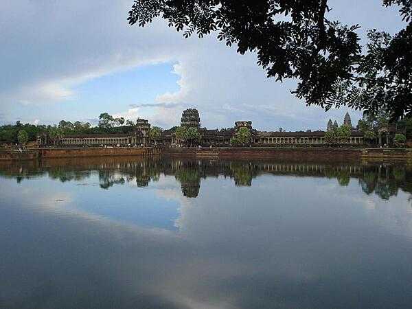 A portion of the sprawling Angkor Wat temple complex as viewed across a moat.