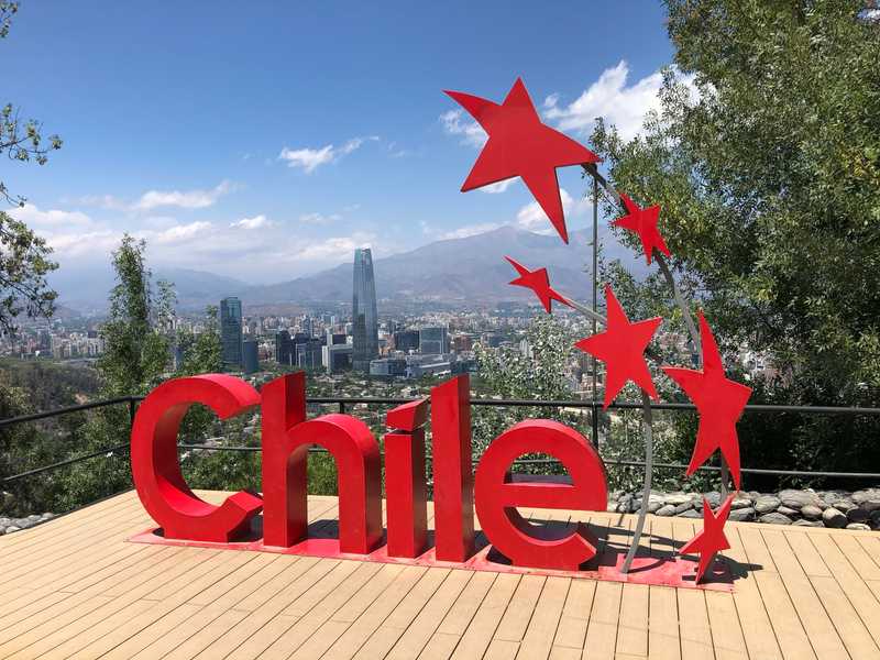 An overlook and sculpture along the walking trail above the Santiago, Chile, business center provides an expansive view. At over 300 m (980 ft), Torre Costanera, shown in the background, is one of the tallest buildings in the southern hemisphere.