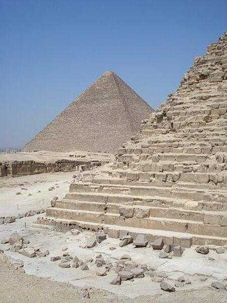 A view of a corner of the Khafre     pyramid reveals its stair-step construction. The Great Pyramid of Khufu appears in the distance.