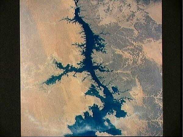 The Aswan High Dam (top of photo) is 4 km (2.5 mi) across and 111 m (364 ft) high. Completed in 1971, it was constructed to supply cheap hydroelectric power to both Egypt and Sudan by impounding, controlling, and regulating the flood waters of the Nile River in Lake Nasser, the world&apos;s second largest artificial lake. The lake extends over 800 km (500 mi) in length, covers an area of some 5,200 sq km (2,000 sq mi) and is as much as 107 m (350 ft) deep at the face of the dam. Click on photo for higher resolution. Image courtesy of NASA.