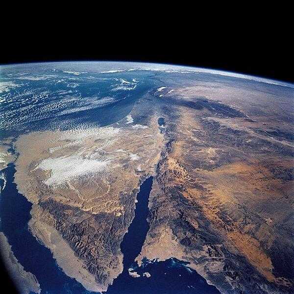 A view of the Sinai Peninsula and the Dead Sea rift area. The left side of the view is dominated by the great triangle of the Sinai peninsula, which is partly obscured by clouds. The Gulf of Aqaba is the finger of the Red Sea (bottom center) pointing north to the Dead Sea, the small body of water near the center of the view. The gulf and the Dead Sea are northerly extensions of the same geological rift that resulted in the opening of the Red Sea. The Gulf of Suez appears in the lower left corner. Click on photo for higher resolution. Image courtesy of NASA.