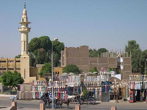 A streetside clothes market in Luxor with a minaret in the background.