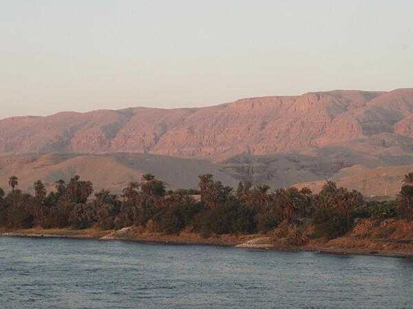 View along the Nile River at sunset south of Luxor. The land is green close to the river where is can be irrigated. Otherwise, it is desert.