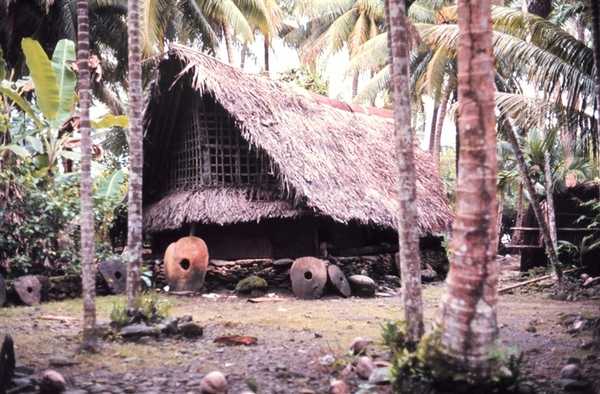 Native home with Yapese money stones (rai stones) indicating great wealth. Such stones were mined on Palau and carried by outrigger canoe 500 km (300 mi). Money stones were quarried from stalactites in limestone caves. Photo courtesy of NOAA/James P. McVey.
