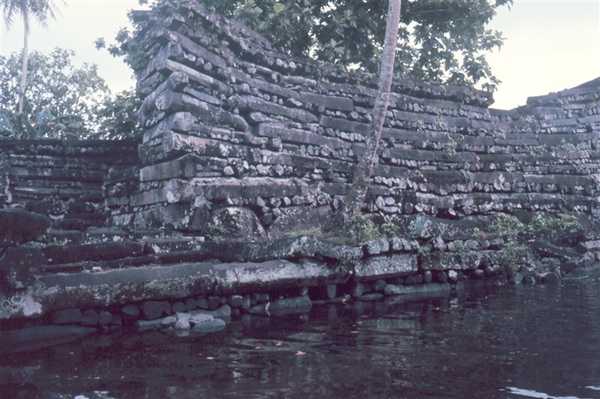 Part of the seawall enclosing Nan Madol, a National Historic Landmark, located on Temwen Island in the present day Madolenihmw district of Pohnpei state, in the Federated States of Micronesia. The ruins were built on 92 artificial islets, stretching out 1.3 km (0.8 mi) in length and 0.6 km (0.4 mi) in width. The islets are surrounded by narrow stretches of water, resembling canals, so it is not surprising that Nan Madol is sometimes referred to as "the Venice of Micronesia."
Basalt boulders, some as heavy as 50 tons, were transported by rafts to Nan Madol from the other side of the island and levered into place with palm tree trunks. The boulders were dragged up log ramps before being piled one atop the other. No mortar was used to hold them together. The rock structures reach as high as 16 m on Pohnwi islet.
 
The roughly rectangular enclosing wall of Nan Madol Central is formed by twelve "seawall" islets framing the entire complex on the northeast, southeast, and southwest sides (Temwen Island forms the NW side). The foundations of these islets were all constructed of columnar basalt and large boulders, the latter particularly common in outer wall facings. The 92 major architectural units (stone- and coral-filled platforms creating artificial islets), are up to about 115 by 100 m in size, and are built above tide level. Postholes found on several islets suggest the construction of thatched-roofed wooden structures on top of the platforms, similar to those known locally. Photo courtesy of NOAA.