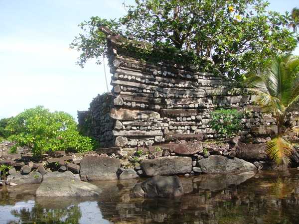 The Nan Madol ruins are on a coral reef in a lagoon on the tiny island of Temwen, adjacent to the eastern shore of the island of Pohnpei in the Federated States of Micronesia. Carved basalt stones carefully placed on top of each other in a crisscross pattern formed the walls of each of the 130 buildings. Some individual stones are light enough that a single person could carry them, while the heaviest of the basalt pillars weigh 45,000 kg (100,000 lbs) each. The buildings stand on a foundation of natural coral that lies just below the water's surface.