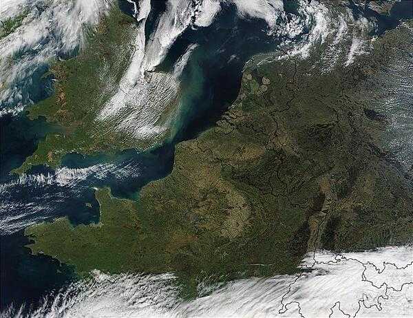 This satellite photo shows Northwest Europe. Visible are the Republic of Ireland (top leftmost), the United Kingdom (top left), France (middle left), Belgium (middle), the Netherlands (top middle), Germany (right), Denmark (top right), Luxembourg (between France, Germany, and Belgium), Switzerland (bottom middle), Italy (bottom middle), and Austria (bottom right); the latter three all cloud covered. The city of Paris is the gray area in northern France. Image courtesy of NASA.