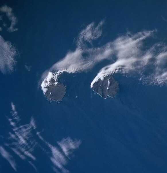 The Crozet Islands (Îles Crozet) are a sub-Antarctic archipelago of small islands in the southern Indian Ocean. They form one of the five administrative districts of the French Southern and Antarctic Lands. This photo from a Space Shuttle mission, taken on 14 December 1998, shows the easternmost islands in this group, Île de la Possession and Île de l'Est. With an area of 150 sq km, Île de la Possession is the largest island of the group and the only inhabited one. It has a rugged landscape of mountains cut by deep glaciated valleys. The coastal areas and valleys are covered with herbaceous sub-Antarctic vegetation. The island's few inhabitants staff of the Alfred Faure Research Station at the eastern end of the island, which has a capacity of about 20 people. Île de l'Est, the easternmost in the archipelago, lies about 20 km east of Île de la Possession. It is the most mountainous isle in the archipelago, with a highest point of 1,090 m. Its landscape is mainly bare rock with a rugged coastline of high cliffs; it is dissected by several steep-sided valleys of glacial origin. Photo courtesy of NASA.
