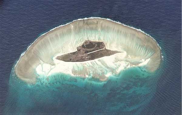 The small island of Juan de Nova, one of the îles Eparses (scattered islets) in the Indian Ocean to the west of Madagascar, was photographed by the Space Station Expedition 5 crew on 11 August 2002. At the top of the photograph it is just possible to make out the wreck of the cargo ship SS Tottenham, which ran aground in 1911 on the islands southwest coast. The northeast coast is dominated by a shallow lagoon. The island is known as a nesting site for green turtles and supports colonies of sooty and greater crested terns. Photo courtesy of NASA.