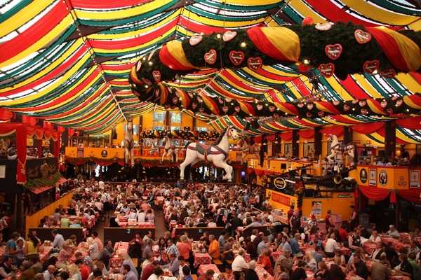 Oktoberfest, held annually in Munich, Bavaria, is a 16- to 18-day folk festival (the world's largest) running from mid- or late-September to the first Sunday in October. More than six million people from around the world attend the event every year. The view shows the interior of one of the massive tents set up to serve food and beer to visitors. The celebration began in 1810, with the the marriage of Crown Prince Ludwig of Bavaria to Princess Therese von Sachsen-Hildburghausen, when the Bavarian royalty invited the citizens of Munich to join in the festivities.