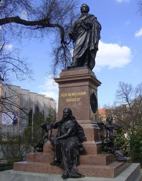 This 6 m- (20 ft-) tall bronze statue of composer Felix Mendelssohn in Leipzig is a replica of an original erected in 1892, but razed by the Nazis in 1936 due to his Jewish heritage. It stands on a granite pedestal with Euterpe, the Greek muse of music, and a pair of winged cherubs playing a violin and flute at his feet on the granite steps.  Dedicated in 2008 in recognition of his 200th birthday, the original statue previously stood in front of the famed Leipzig Conservatory of Music (today the Leipzig Academy of Music and Theater) that he established in 1843; the reproduction stands near Leipzig’s Saint Thomas Church and the gravesite of Johann Sebastian Bach - a composer Mendelssohn greatly admired and whose music he reintroduced to 19th-century audiences.