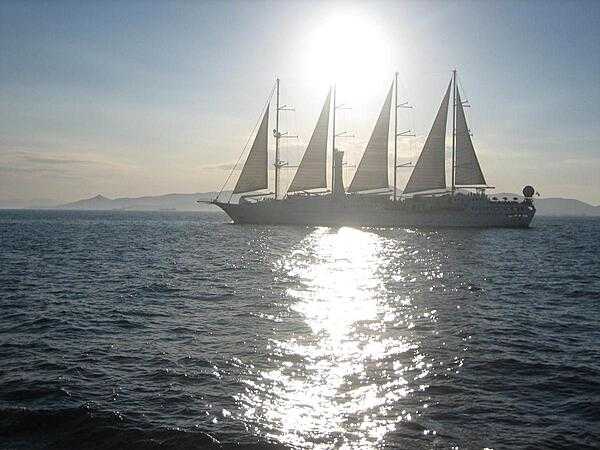 A sailing vessel plies the sun-drenched Aegean Sea.