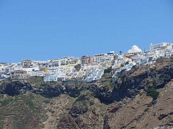 Houses and hotels perched on top of 300 m (980 ft) cliffs on Santorini/Thera Island. The cliffs show the many layers of volcanic eruptions over time.