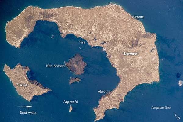 The islands in this photo - located approximately 120 km (75 mi) north of Crete in the Aegean Sea - are arranged in an oval shape. They are all that remains of what was once a large, circular volcano. The largest island in the ring is the tourist mecca of Santorini (also known as Thera), while the other islands are Thirasia and Aspronisi. The three pieces are what remains after an enormous eruption destroyed most of a volcanic island. Water from the Aegean Sea rushed in to fill the void, forming the central, 12 km-long (7.5 mi) lagoon.

The lagoon is surrounded by high, steep cliffs on three sides. Several towns occupy the top of these impressive, near-vertical cliffs (roughly 300 m or 1,000 ft), appearing as white stipple patterns. Santorini is one of the most famous tourist islands on Earth. Ships arrive at the bottom of the cliffs near the town of Fira. Tourists then climb a switchback road up the cliffs to the town - a classic Greek village on a cliff face looking out into the great lagoon.

The caldera explosion that made this lagoon is one of the largest known to geologists. An estimated 100 cu km of material blew out of the volcano, four times as much as the well-recorded eruption by Krakatoa in 1883. Santorini has been designated a “Decade Volcano” because it poses more than one volcanic hazard to people living near it. The date of the Santorini explosion has been carefully researched and is now known to have taken place between 1600 and 1627 B.C. Archaeological excavations at the town of Akrotiri are revealing exciting remains of a Minoan-age town with streets, three-story houses, and frescoes well preserved under ash layers, much like those preserved at Pompeii.

Since the volcano is still active, the central peak has grown and then erupted repeatedly. Nea Kameni is the most recent peak of the underwater volcano to appear above water (popping up in 1707). There have been three eruptions in the 20th century alone. Image courtesy of NASA.