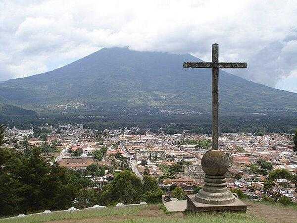 A cross overlooks the city of Antigua in the central highlands of Guatemala; the Volcan de Agua (Volcano of Water) appears in the background.