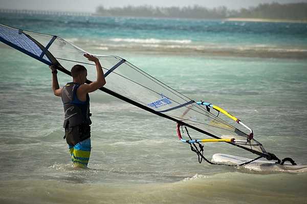 A sailor assigned to US Naval Support Facility Diego Garcia windsurfs in the lagoon. The sheltered water body offers the opportunity for a variety of water sports. Photo courtesy of the US Navy/ Mass Communication Specialist 3rd Class Alex Smedegard.