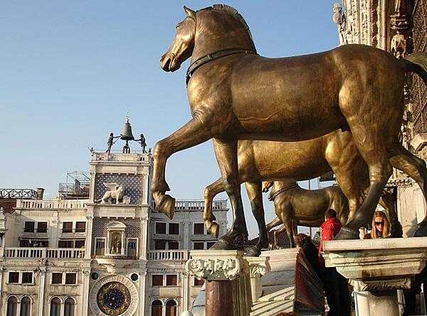 View of St. Mark&apos;s Square in Venice showing the famous Greek horses and the astronomical clock. The bronze horses were originally installed at the Hippodrome in Constantinople and so date back to at least the 4th century. In 1254 they came to Venice where they remained until 1797 when they were brought to Paris by Napoleon. In 1815 they were returned to Venice. The originals are now in St. Mark&apos;s Museum. The original astronomical clock was built between 1496-99. It has been renovated many times, most recently in 1996.