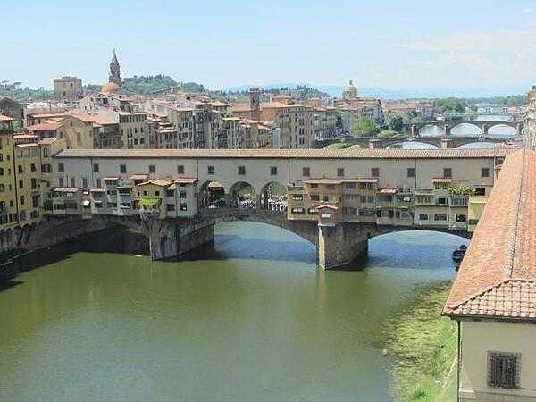The Ponte Vecchio (Old Bridge) spans the Arno River in Florence at its narrowest point. The current structure dates to 1345. As it has for centuries, the bridge still houses shops on either side of the roadway.