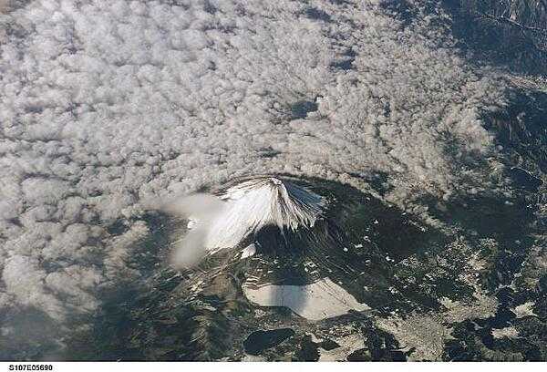 Mt. Fuji on the island of Honshu as seen from the space shuttle. The snow-capped inactive volcano, surrounded at lower levels by clouds in this image, lies several miles south of Tokyo. Image courtesy of NASA.