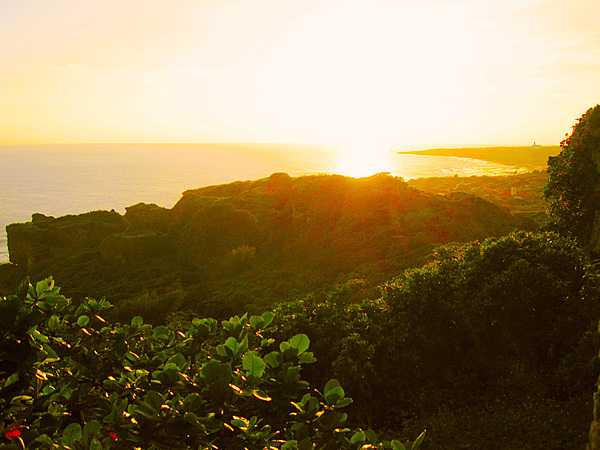 Sunrise over a verdant Okinawan shoreline.