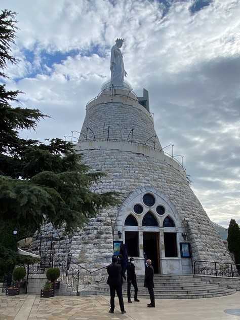 The Shrine of Our Lady of Lebanon is a Marian shrine and a pilgrimage site in Harissa, Lebanon.  Erected in 1907 and dedicated in 1908, the 11.7 metric ton (13 ton) bronze statue painted white stands 8.5 m (27 ft) tall and stretches her hands towards nearby Beirut.  The statue’s stone pedestal is nearly 20 m high (66 ft) and encases the Our Lady of the Light Chapel. Our Lady of Lebanon is one of the most important shrines in the world honoring Mary, Mother of Jesus.