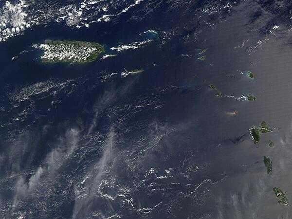 A view of Puerto Rico (upper left) and the isles of the Lesser Antilles. The Soufriere Hills Volcano on the island of Montserrat began emitting steam and ash on 9 February 2006. Low-level activity continued for several days. The volcano produced another plume on 20 March 2006, which is captured on this image. The volcano&apos;s pale beige ash plume blows westward over the Caribbean Sea. The red outline shows where the satellite detected a thermal anomaly, an area where the ground surface was significantly hotter than its surroundings. Image courtesy of NASA.