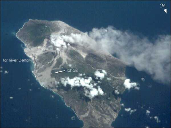 Monserrat's frequent cloud cover can make getting remote sensing images difficult. This view from the International Space Station taken 9 July 2001 recorded a vigorous steam plume emanating from the summit of Soufriere Hills. The image also reveals the extensive volcanic mud flows (lahars) and new deltas built out from the coast from the large amounts of volcanic debris delivered downstream by the rivers draining the mountain. As a small island (only 13 x 8 km), all of Montserrat was impacted by the eruptions. Image courtesy of NASA.