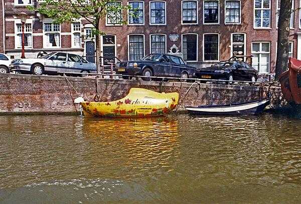 A wooden shoe-shaped boat on an Amsterdam canal. Most of the city&apos;s canals were built in the 17th century. The old city center of Amsterdam is the focal point for architectural styles prior to the end of the 19th century; outlying areas display more recent architectural styles.