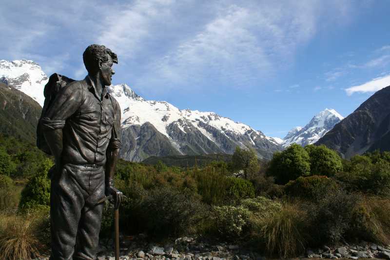 A memorial statue to Edmund Hillary shows the explorer as a young man gazing toward the mountains.  (In 1953, Hillary was one of the first two people to successfully scale Mount Everest, Earth's tallest peak above sea level.)  The monument was commissioned by the Hermitage Hotel in Aoraki/Mount Cook National Park (South Island) and stands on its grounds to recognize the fiftieth anniversary of Hillary's ascent of Aoraki/Mount Cook in 1948, which influenced his early climbing career.