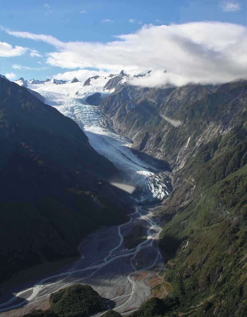 As seen from the air, Fox Glacier, in the Aoraki/Mount Cook range, has a steep but straight flow from the upper bowl to sea level where it forms a glacial river.