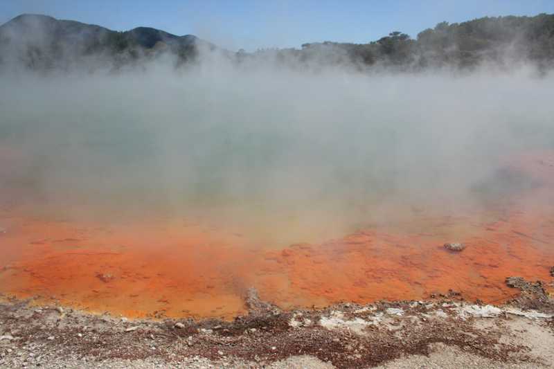 Champagne Pool, located in Wai-O-Tapu Thermal Park, is a large hot spring on the North Island. Antimony-rich deposits around the rim turn the soil a bright orange color. Surface temperatures are near boiling.
