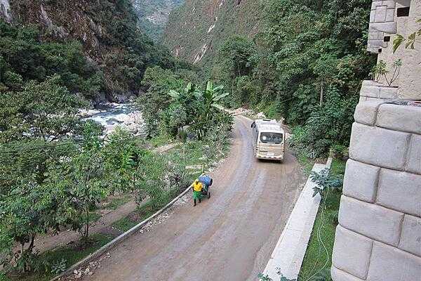 A bus taking tourists to the sacred Incan city of Machu Picchu passes a shopkeeper wheeling his wares to Aguas Calientes (Hot Waters), the nearest access point to the mountaintop city.