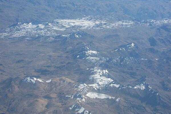 Aerial view contrasting snow and semi-arid terrain in the Andes.