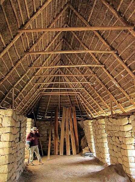 The inside of a large Machu Picchu structure with a thatched roof.