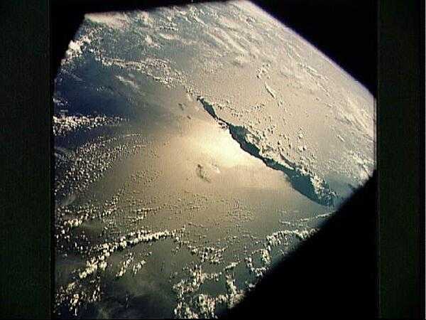 A sun glint on the southwestern Pacific Ocean as photographed from an Apollo spacecraft in Earth orbit. The island is Bougainville in Papua New Guinea; the horizon of the Earth appears in the background. The picture was taken at an altitude of 231 km (143 mi). Image courtesy of NASA.