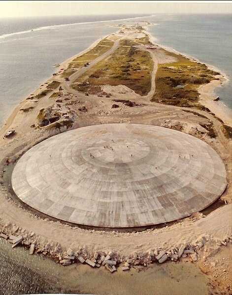Aerial view of Runit Dome (or Cactus Dome) on Runit Island in Enewetak Atoll. Between 1977 and 1980, the crater created by the Cactus shot of Operation Hardtack I was used as a burial pit to inter 84,000 cubic meters of radioactive soil scraped from the various contaminated Enewetak Atoll islands. The Runit Dome was built to cover the material. Photo courtesy of US Department of Defense.