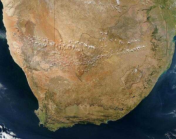 Satellite view of South Africa. The rugged Great Karoo semi-desert region makes up much of the central and western part of the country. The brown and orange landscape that surrounds South Africa&apos;s northwestern borders is the Kalahari Desert, a vast sand basin marked by dunes and dry savannah vegetation. The southern edge of the desert is defined by the Orange River, which also forms South Africa&apos;s northwestern border with Namibia. Within South Africa is the enclave of Lesotho. Northeast of Lesotho is the smaller country of Eswatini (formerly named Swaziland). Photo courtesy of NASA.
