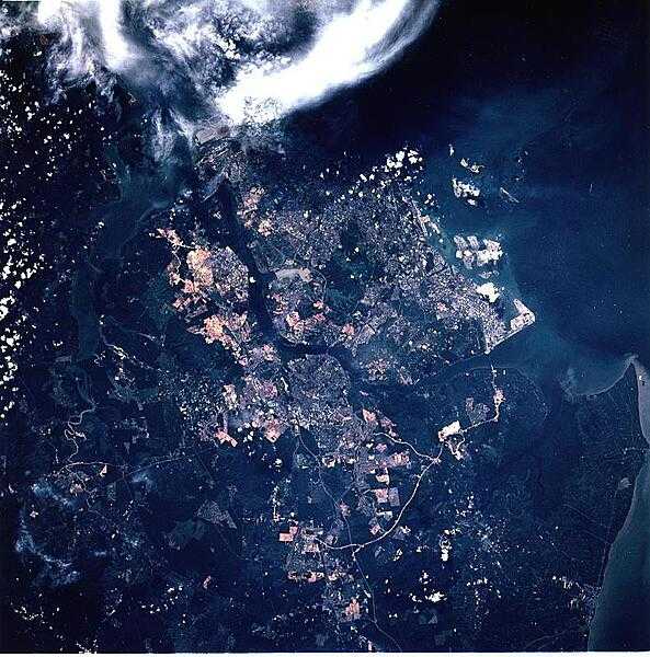 The city of Singapore (center of image), which now encompasses the whole island of Singapore, may be seen in this northeast-looking view. Singapore has a large natural harbor and is strategically located on the southern tip of the Malaysian Peninsula between the Strait of Malacca to the west (extreme bottom left), and the South China Sea to the east (not visible). Image courtesy of NASA.