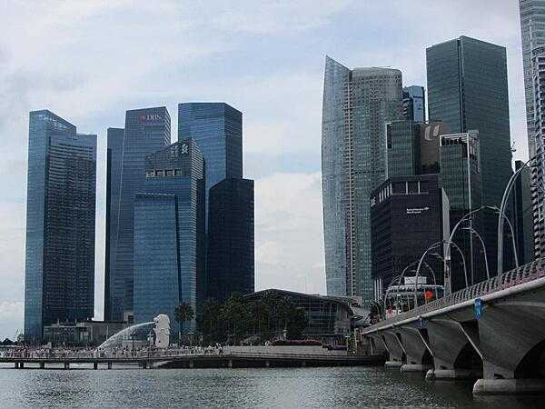Skyline of the Singapore business district. The larger of two Merlions (half fish-half lion creatures) may be seen spouting along the pier. Singapore is one of the world&apos;s leading financial centers.
