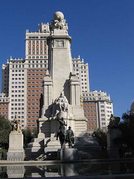 The Monument to Miguel de Cervantes in the center of the Plaza de España in Madrid, Spain, was commissioned by King Alfonso XIII in 1915, on the 300th anniversary of the writer’s death. Cervantes is widely regarded as the greatest writer in the Spanish language.  The main part of the monument was erected in 1929, but the structure was not fully finished until the 1960’s with the addition of the flanking Aldonza and Dulcinea statues. Standing 34 m (111.5 ft), the stone monolith includes a statue of a seated Cervantes holding a copy of Don Quixote, allegories of Literature, Military Value, and Mysticism; and a crowning Earth globe at the top surrounded by five women representing the five continents. A detached bronze statue of two of Cervantes’ best known literary characters, Don Quixote and Sancho Panza, stand in front of the monolith.