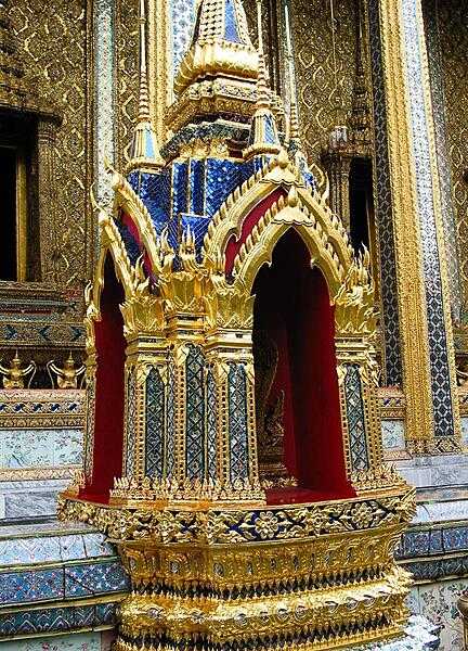 At the Grand Palace in Bangkok; the Palace complex features brightly colored buildings, golden spires, and glittering mosaics.  This close-up highlights the widespread and effective use of mirrored tiles in the construction process.