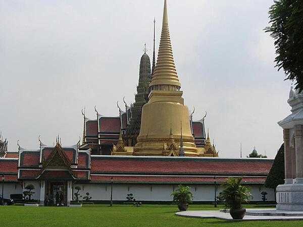 View within the Grand Palace in Bangkok showing the golden Phra Siratana Chedi. A chedi, or stupa, is a mound-like reliquary containing Buddhist relics. The chedi is on the grounds of the Temple of the Emerald Buddha.