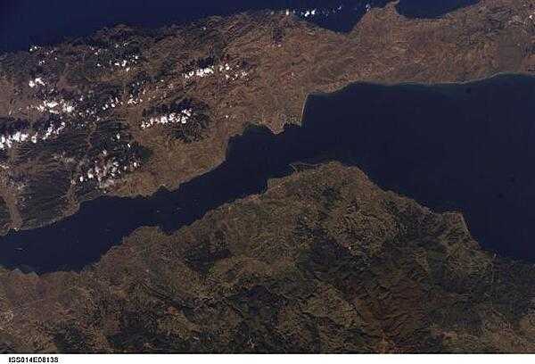 The city of Gallipoli (Gelibolu in Turkish; light gray to pink area in center of photo) sits at a crossroads between the Sea of Marmara (to the right) and the Dardanelles Strait (which leads to the Aegean Sea). Water in the Strait flows in both northeast and southwest directions due to opposite surface and undercurrents. Several ships are visible in the Strait to the southwest of Gallipoli (center left). Image courtesy of NASA.